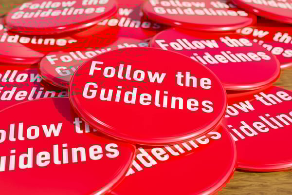 Red badges laying on the table with the message follow the guidelines